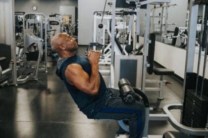 older man using strength training equipment at gym